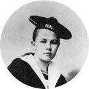 Photographie en noir et blanc d'un jeune en uniforme de marin, portant un chapeau incliné sur le côté. Photographie en noir et blanc d'un jeune en uniforme de marin, portant un chapeau incliné sur le côté.