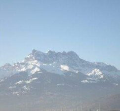 Un sommet de montagne recouvert de neige se dresse sous un ciel bleu clair, avec un premier plan brumeux. Un sommet de montagne recouvert de neige se dresse sous un ciel bleu clair, avec un premier plan brumeux.