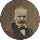 Portrait ovale en noir et blanc d'un homme âgé avec une barbe, portant un manteau et un nœud papillon, regardant directement la caméra. Portrait ovale en noir et blanc d'un homme âgé avec une barbe, portant un manteau et un nœud papillon, regardant directement la caméra.