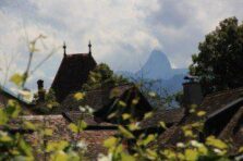 Les toits et la verdure dominent le premier plan, avec un sommet de montagne s'élevant à l'arrière-plan lointain et nuageux. Les toits et la verdure dominent le premier plan, avec un sommet de montagne s'élevant à l'arrière-plan lointain et nuageux.