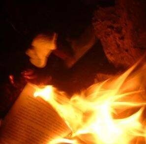 Un livre est englouti par les flammes, avec des pages de texte visibles consumées par le feu. Un livre est englouti par les flammes, avec des pages de texte visibles consumées par le feu.